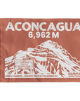 A rectangular brown summit flag featuring a white illustrated mountain and large text reading 'ACONCAGUA 6,962 M' with additional text 'SEVEN SUMMITS - HIGHEST PEAK IN THE AMERICAS' and 'SUMMIT SOMETHING'.