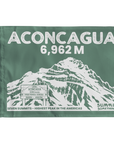 A rectangular green summit flag featuring a white illustrated mountain and large text reading 'ACONCAGUA 6,962 M' with additional summit text along the bottom.