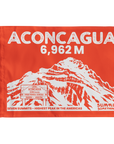 A rectangular orange summit flag featuring a white illustrated mountain and large text reading 'ACONCAGUA 6,962 M' with additional text 'SUMMIT SOMETHING' and 'SEVEN SUMMITS - HIGHEST PEAK IN THE AMERICAS'.