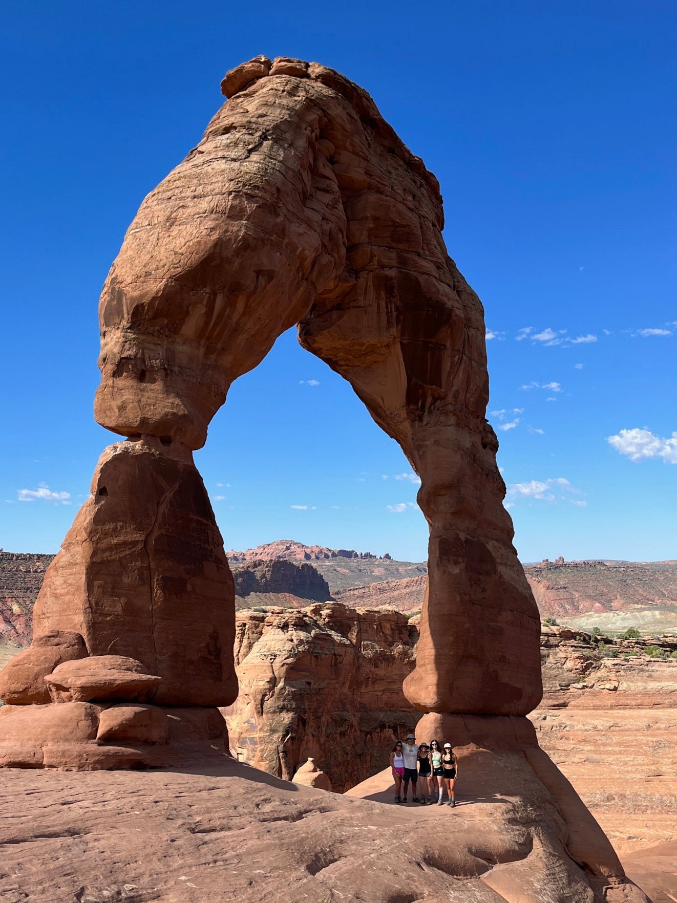 Familiy posing at the base of Delicate Arch in Arches National Park near Moab,  Utah