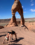 A girl posing in front of Delicate Arch in  Arches National Park near Moab, Utah