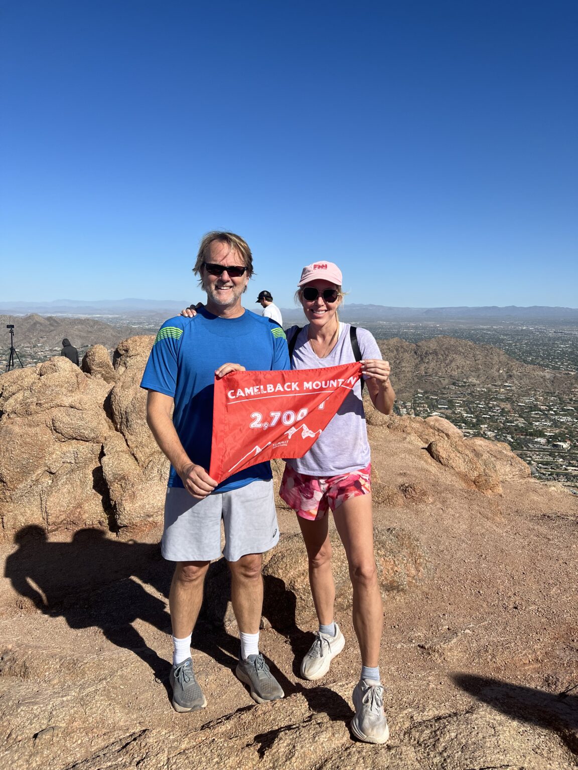 A couple celebrates reaching the Camelback Mountain summit with summit flag made by 5ummit 5omething