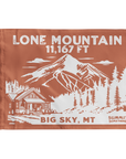 A brown summit flag depicting the classic  dramatic view of Lone Mountain and with Lone Mountain and elevation of in white text the name of Lone Mountain and the 11,167 elevation written in white text at the top and Big Sky, MT written at the bottom.