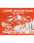 An orange summit flag depicting the classic  dramatic view of Lone Mountain and with Lone Mountain and elevation of in white text the name of Lone Mountain and the 11,167 elevation written in white text at the top and Big Sky, MT written at the bottom.